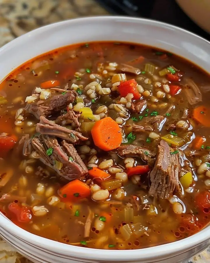 Bowl of delicious Beef Barley Soup garnished with herbs and vegetables