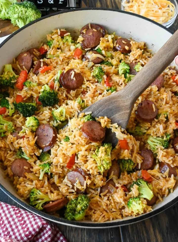 Delicious cheesy sausage rice skillet topped with melted cheese in a skillet.