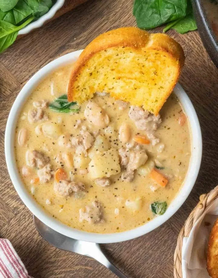 Bowl of Italian Sausage White Bean Soup garnished with herbs
