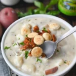 Bowl of New England Clam Chowder topped with parsley and served with oyster crackers.