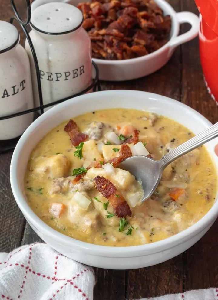 Delicious slow cooker cheeseburger soup garnished with cheese and herbs.