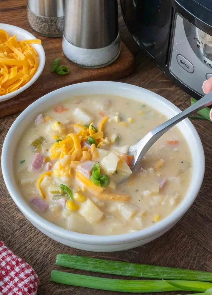 Bowl of slow cooker ham and potato soup topped with herbs.