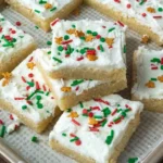 Delicious homemade sugar cookie bars topped with frosting and sprinkles.