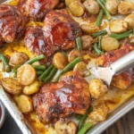 Baked chicken served with potatoes and green beans on a dinner plate.