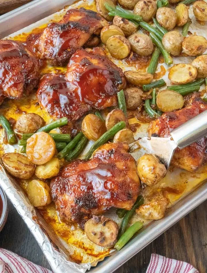 Baked chicken served with potatoes and green beans on a dinner plate.