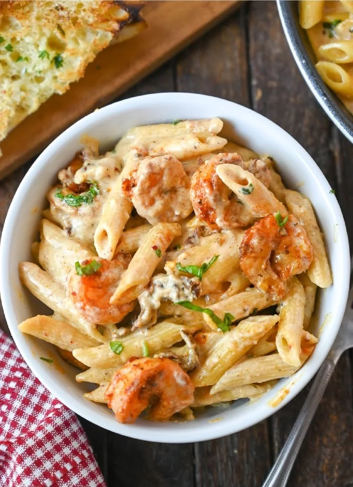Plate of creamy garlic shrimp pasta garnished with parsley and cheese