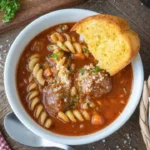 Bowl of Italian meatball soup with fresh herbs and vegetables