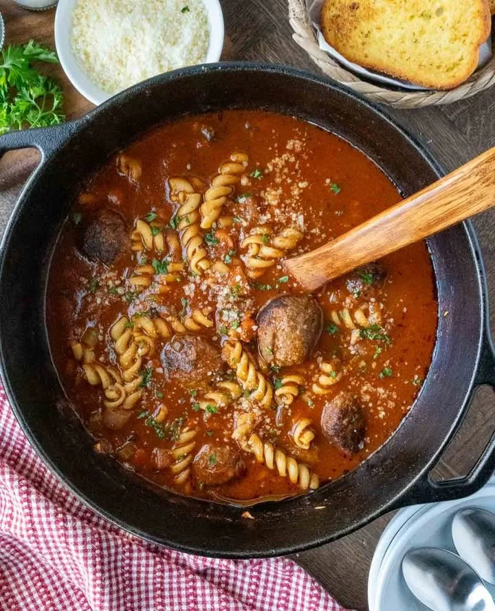 Bowl of Italian meatball soup with fresh herbs and meatballs