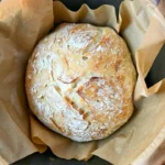 Freshly baked no knead artisan bread loaf on a wooden cutting board