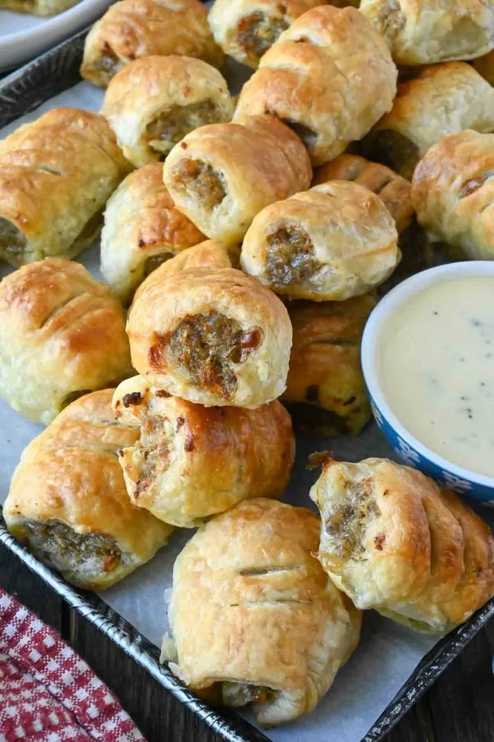 Sausage rolls served with honey mustard sauce on a plate.