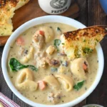 Bowl of hearty Sausage Tortellini Soup with fresh herbs and vegetables.