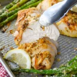 Sheet pan Lemon Herb Chicken with asparagus garnished with fresh herbs.