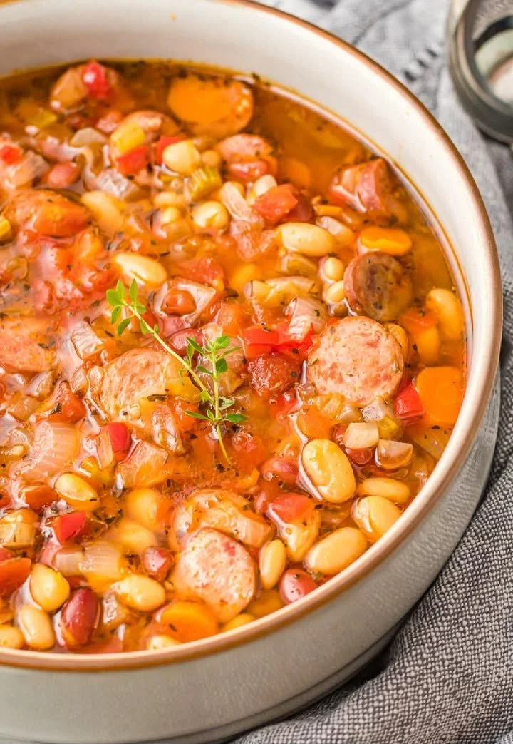 Bowl of slow-cooker sausage three-bean soup with fresh herbs
