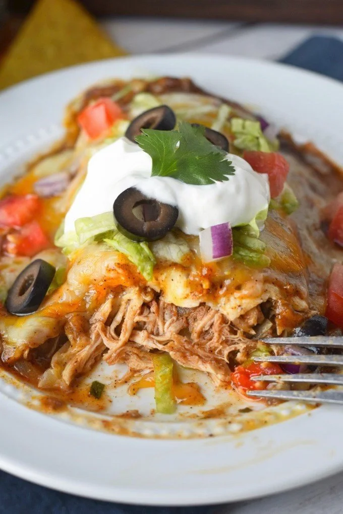 Smothered Chicken Burritos topped with savory sauce and fresh ingredients