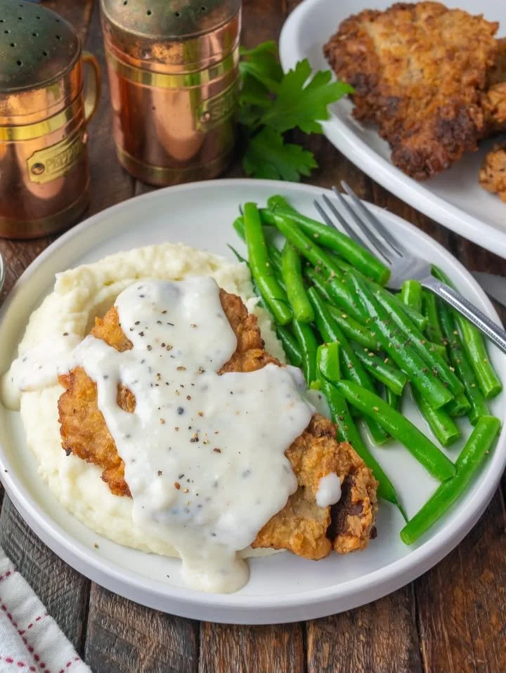 Delicious Texas Roadhouse chicken fried steak with creamy gravy and side dishes.