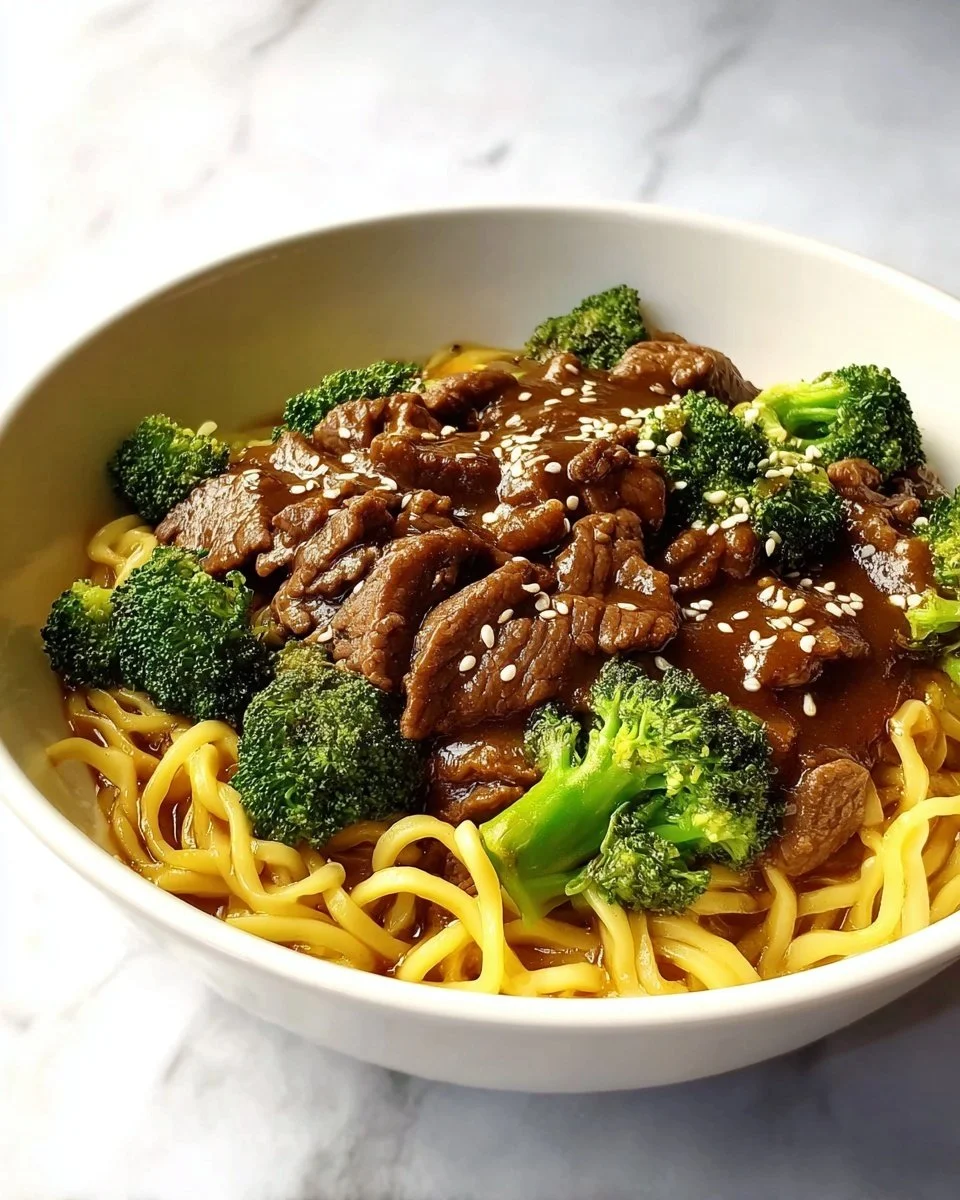 home Delicious Beef and Broccoli Lo Mein served in a bowl with fresh vegetables.