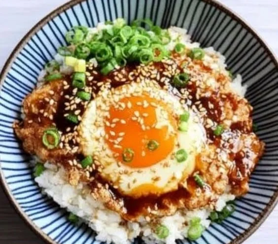 Bowl of Korean egg rice garnished with green onions and sesame seeds