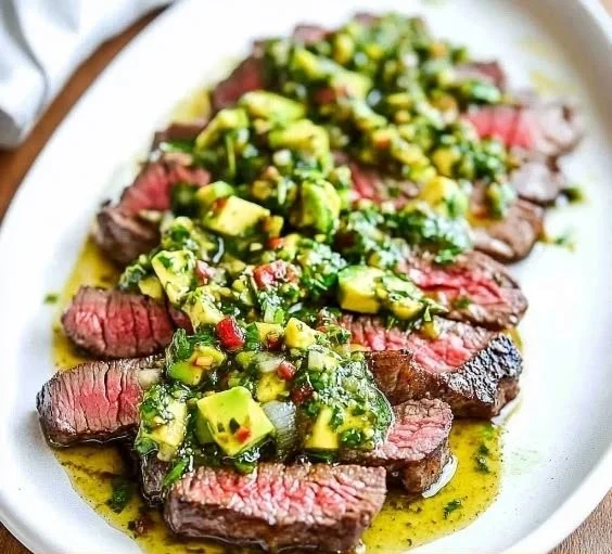 Skirt steak served with avocado chimichurri sauce on a plate.