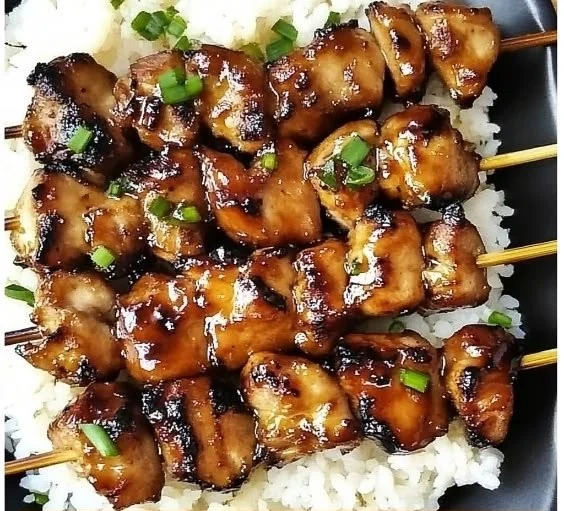 Grilled teriyaki chicken skewers with colorful vegetables on a platter